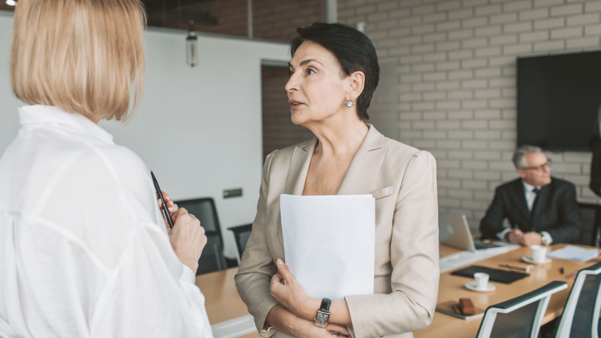 Duas profissionais conversando em pé durante uma reunião de negócios