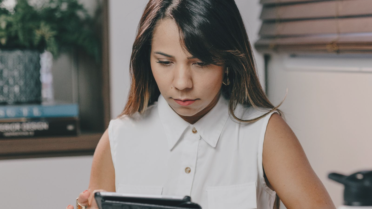 Mulher concentrada usando um tablet em mesa de escritório