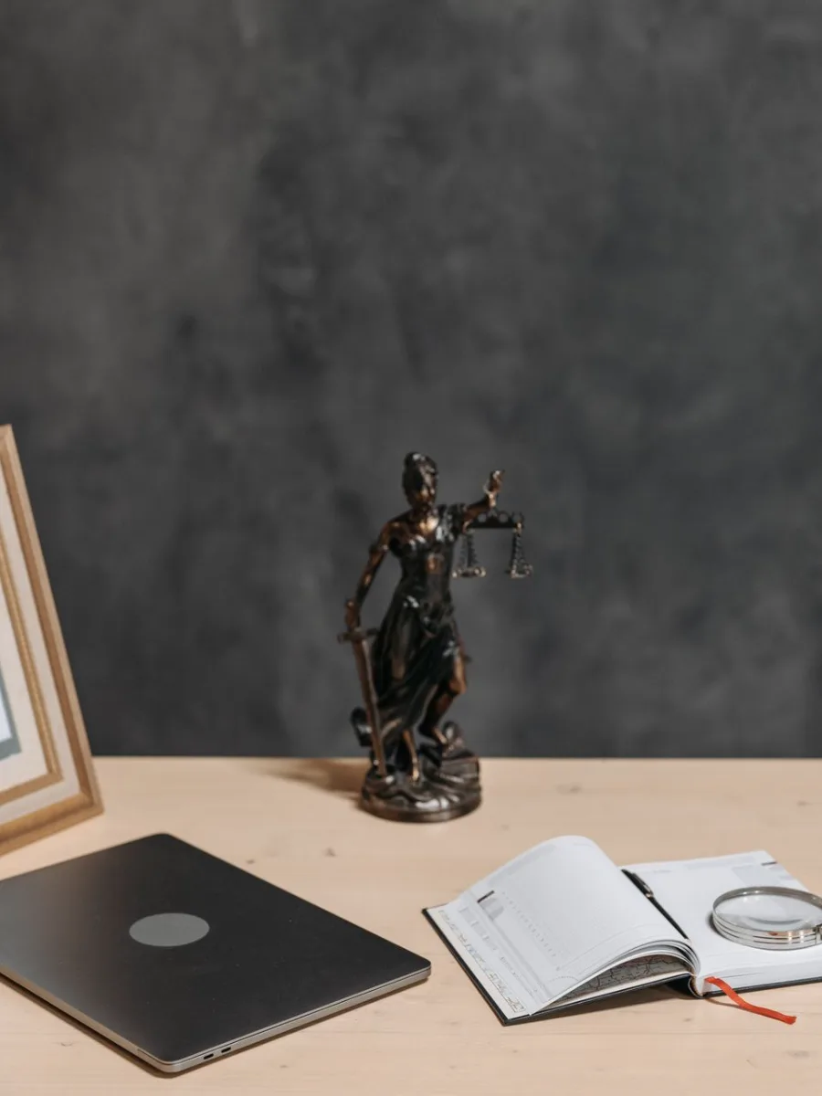 Mesa de escritório de advocacia com estátua da Justiça, diploma e notebook