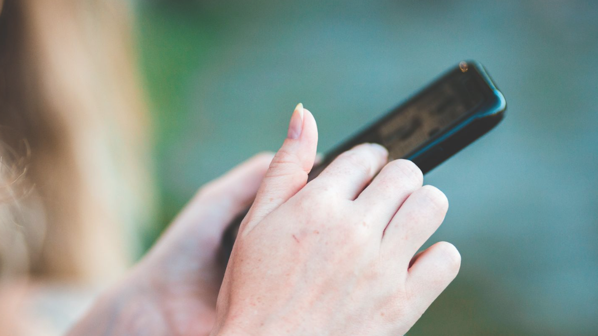 Mão segurando celular, verificando um anúncio no ChatGPT
