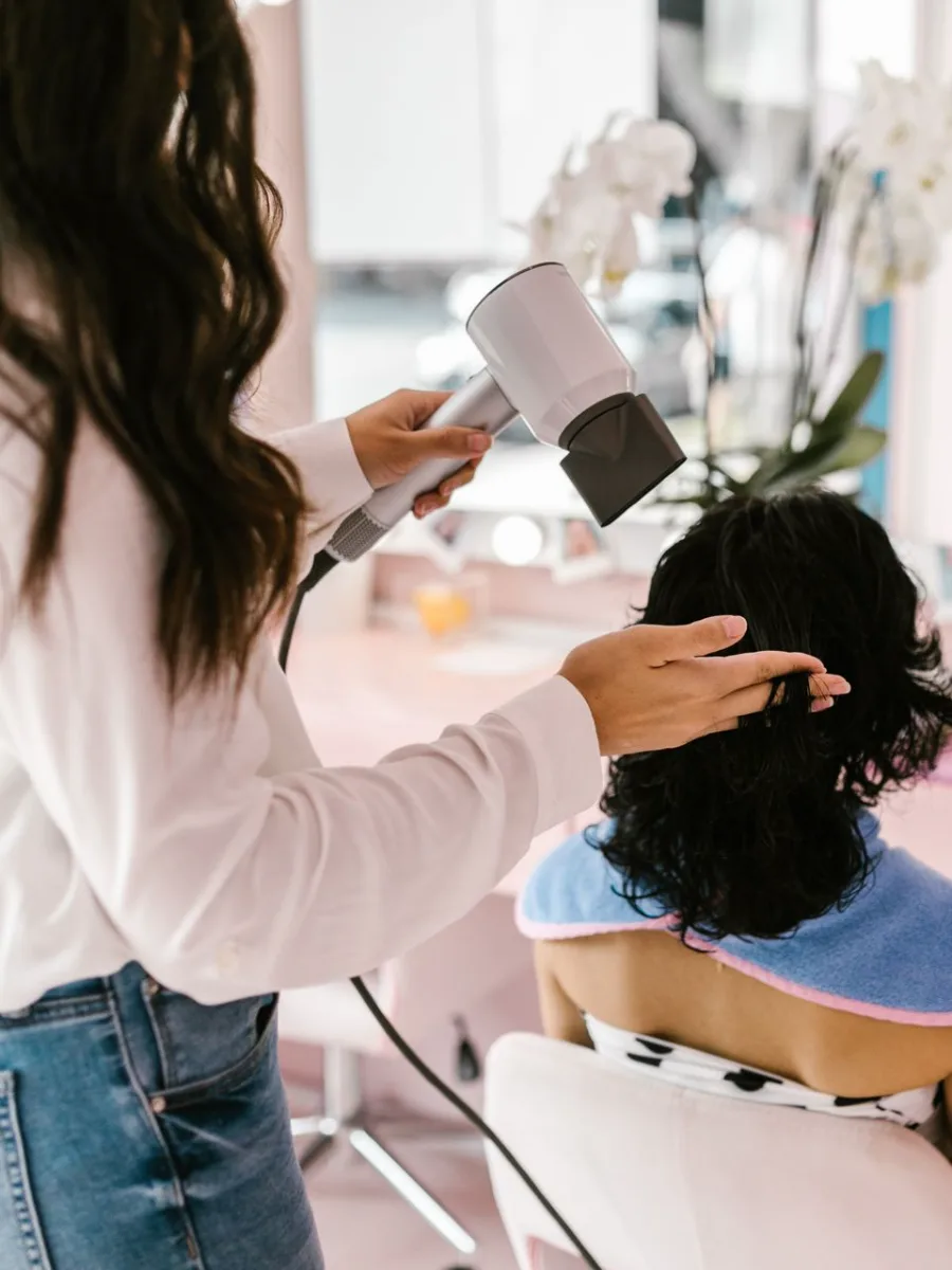 Cabeleireira secando o cabelo de uma cliente em um salão de beleza