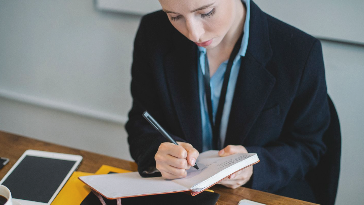 Profissional de marketing anotando em um caderno ao revisar os 4 As do marketing