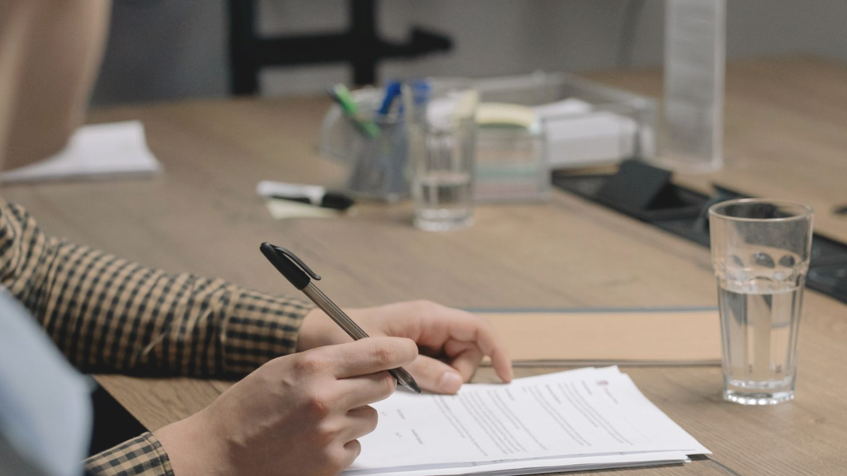 Mão assinando documento sobre mesa, ilustrando o momento em que um projeto mais simples fecha contrato
