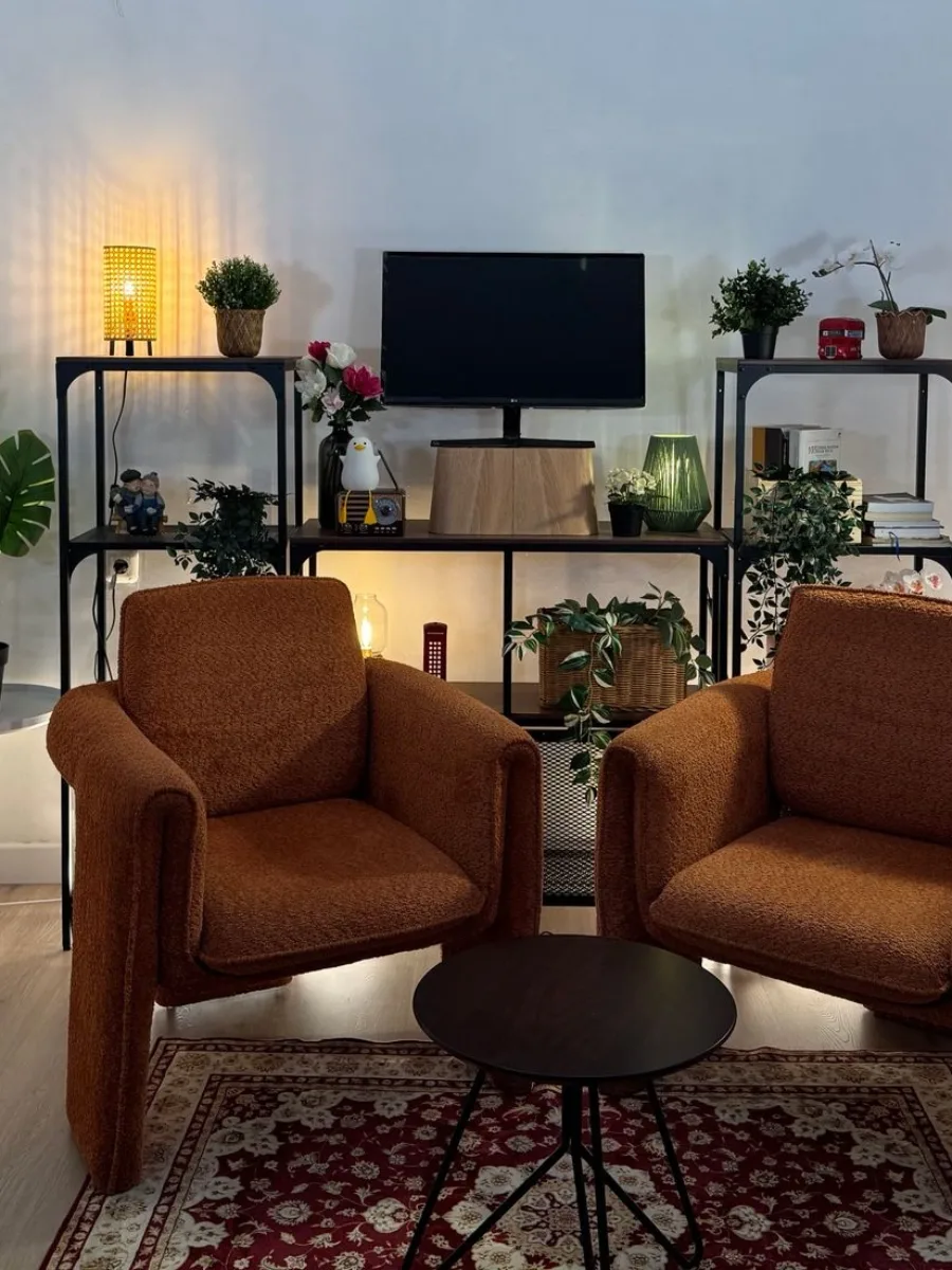 Consultório de psicologia com duas poltronas, mesa de centro e plantas